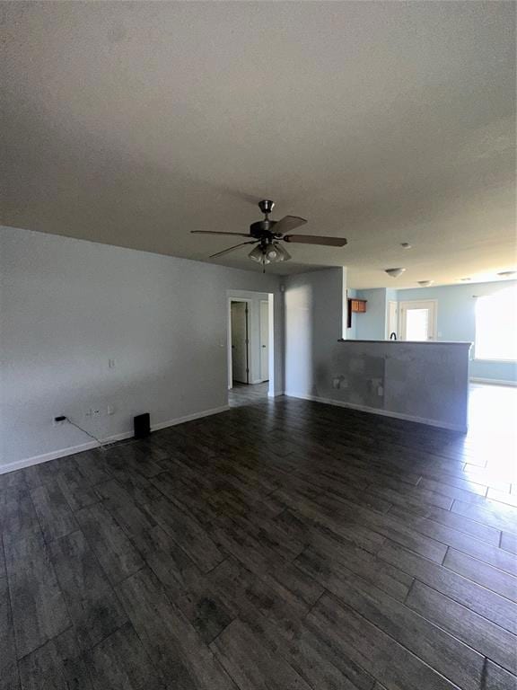 Spare room featuring dark wood-style floors, a ceiling fan, and baseboards