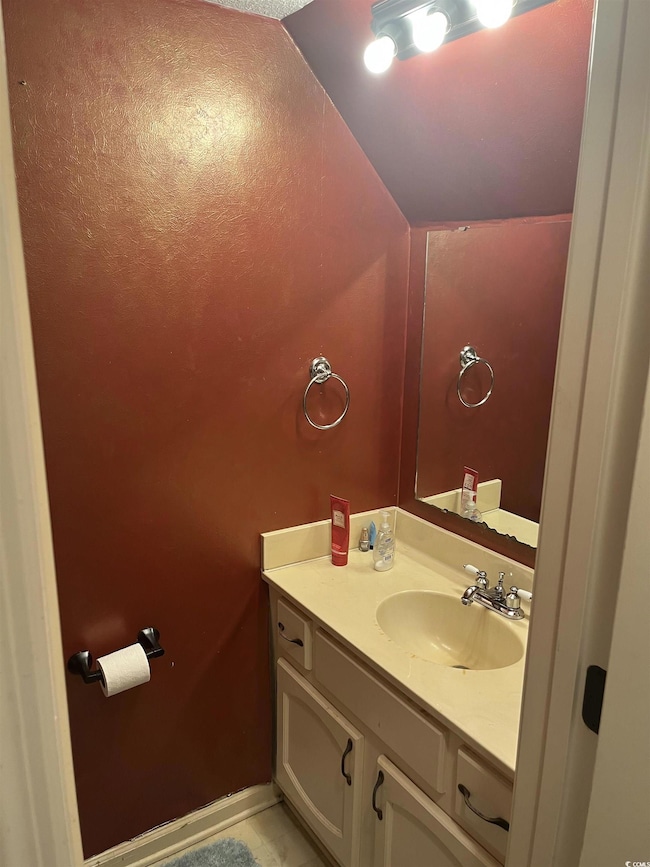 Bathroom with vanity and lofted ceiling