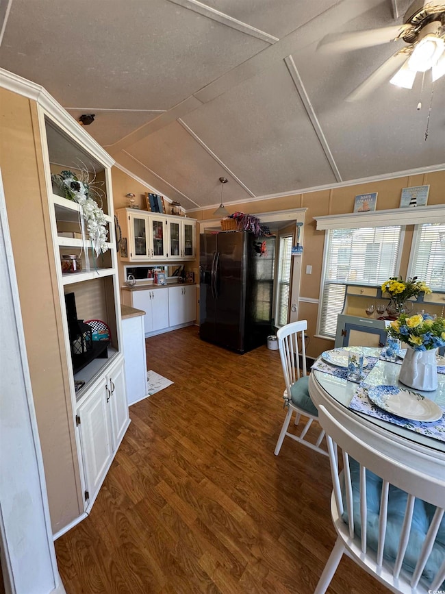 Dining space with dark wood-style flooring, lofted ceiling, ceiling fan, a textured ceiling, and crown molding