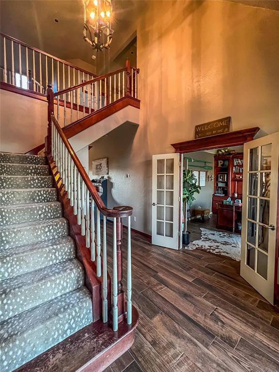 Staircase featuring a notable chandelier, hardwood