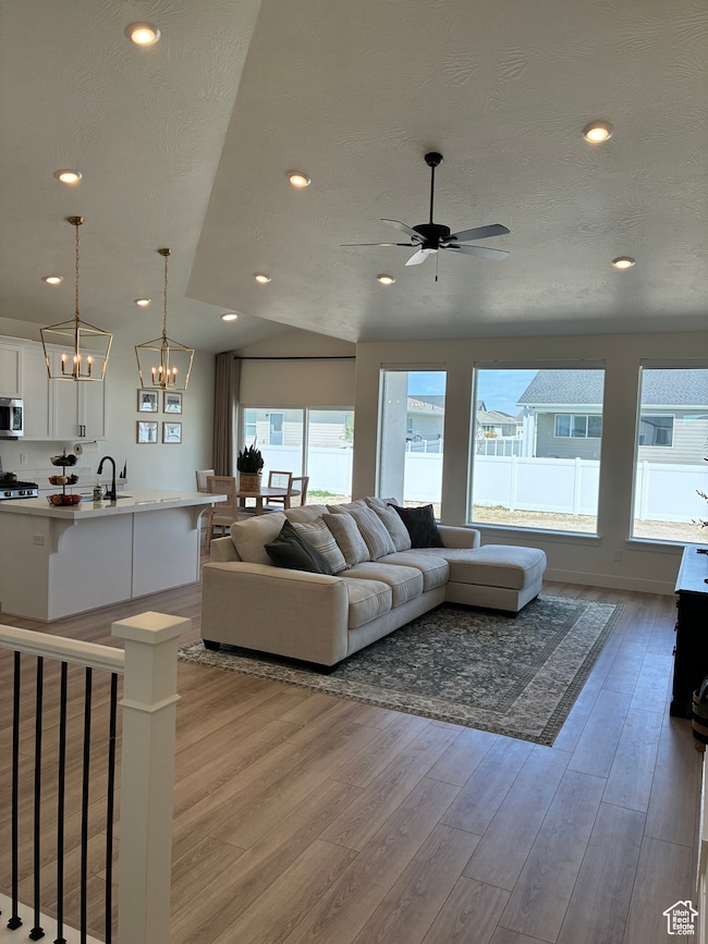 Living area featuring light wood-type flooring, recessed lighting, a chandelier, and vaulted ceiling