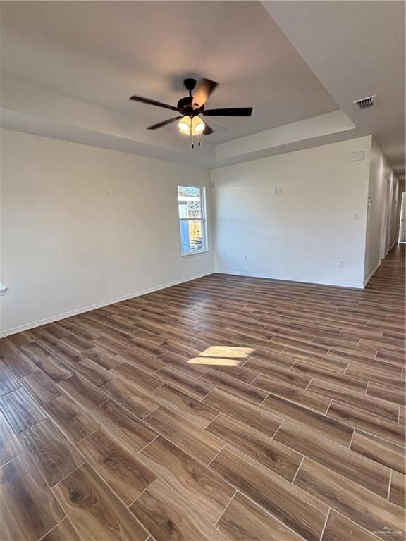 Spare room with ceiling fan and a tray ceiling
