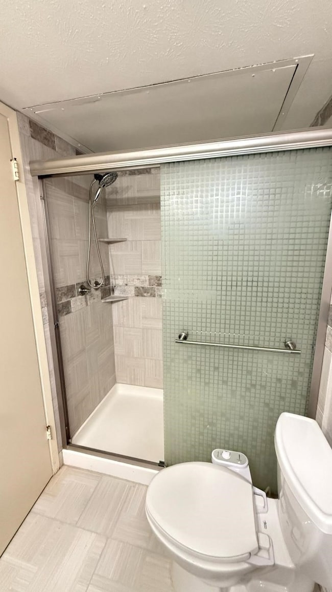 Bathroom featuring toilet and a stall shower