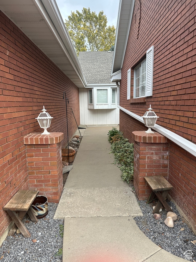Property entrance with brick siding and a shingled roof