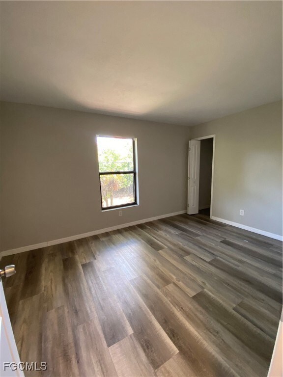Spare room featuring dark wood-type flooring and b