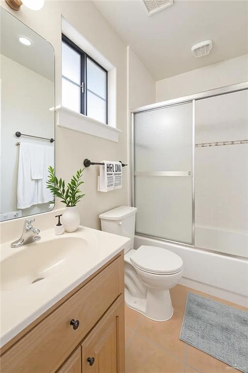 Bathroom featuring enclosed tub / shower combo, light tile patterned floors, and vanity