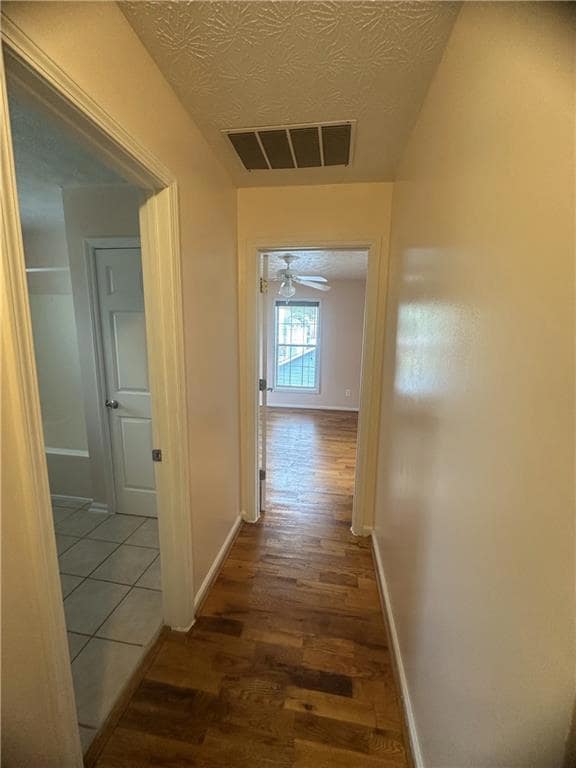 Corridor with wood finished floors and a textured ceiling