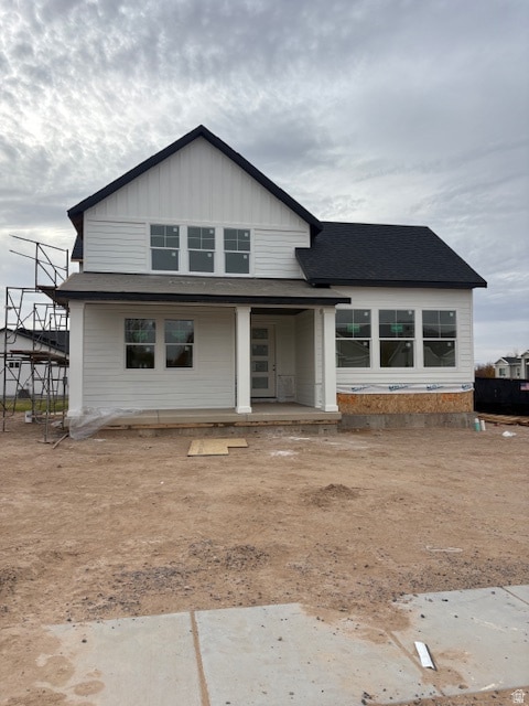 View of front of home featuring a shingled roof, board and batten siding, and covered porch