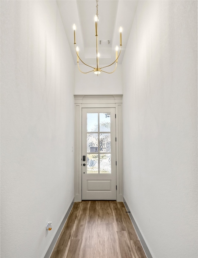 Doorway featuring a chandelier and wood finished floors