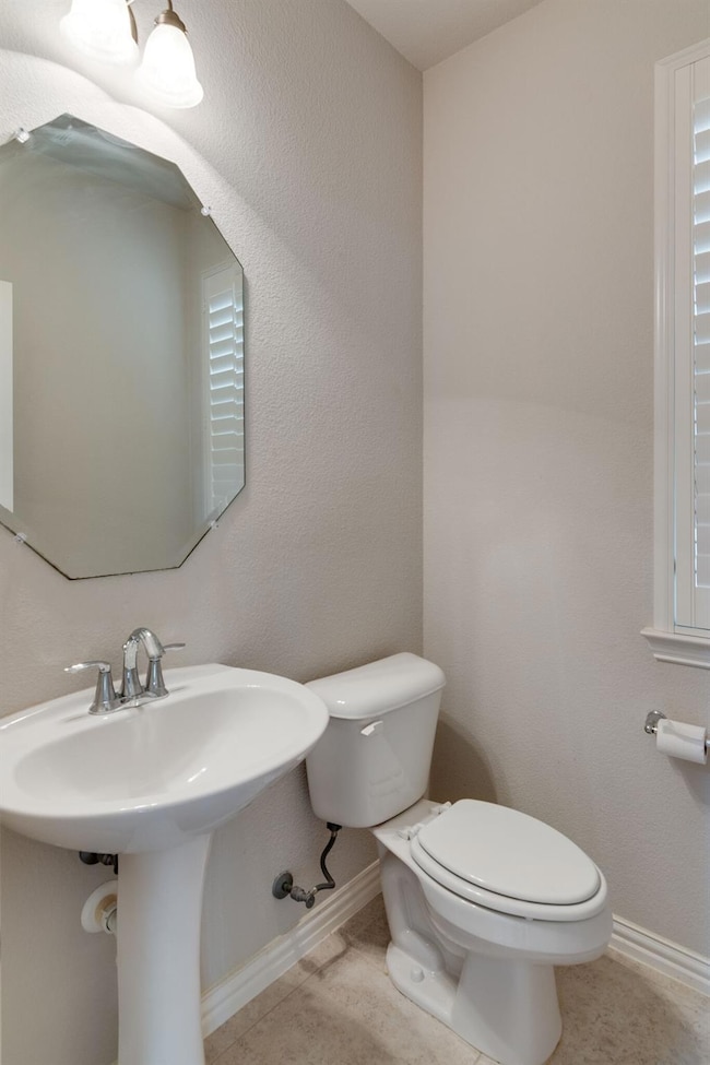 Bathroom featuring toilet, sink, and tile patterne