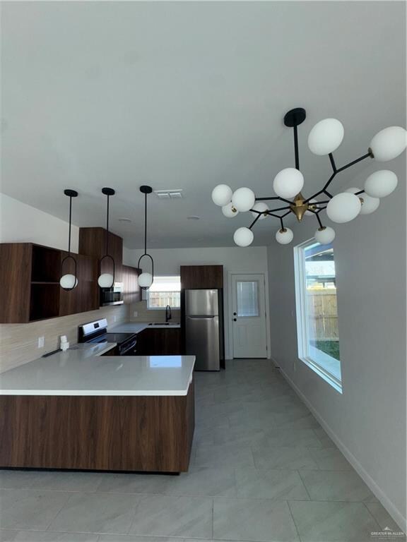Kitchen featuring pendant lighting, decorative backsplash, stove, fridge, and a peninsula