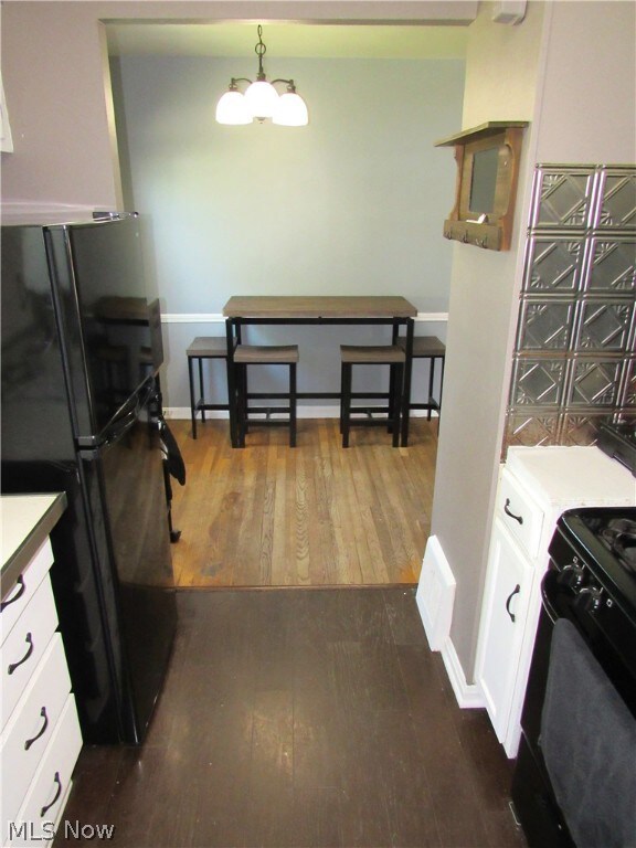 Kitchen featuring a notable chandelier, white cabinets, dark hardwood / wood-style flooring, and black appliances