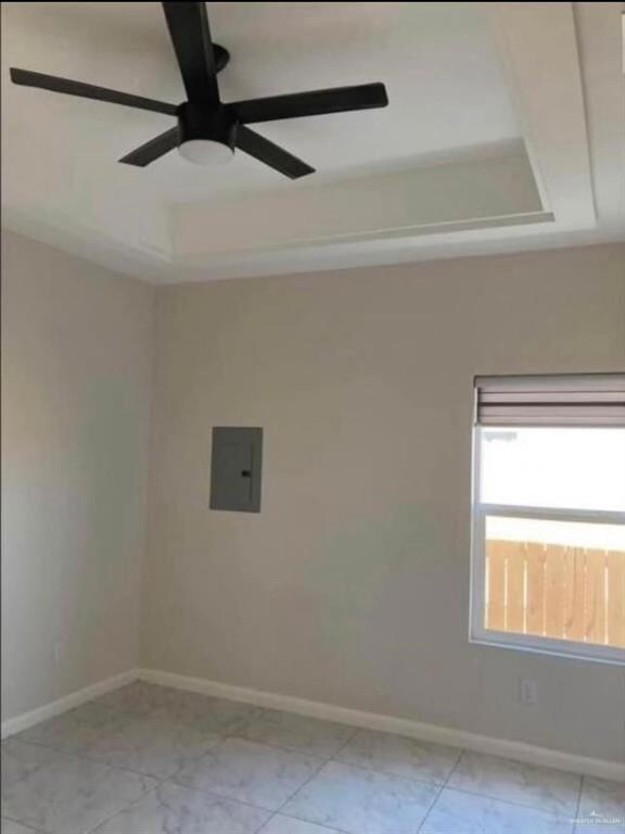 Tiled spare room with ceiling fan and a tray ceiling