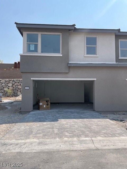 View of front of property with decorative driveway, stucco siding, and a garage