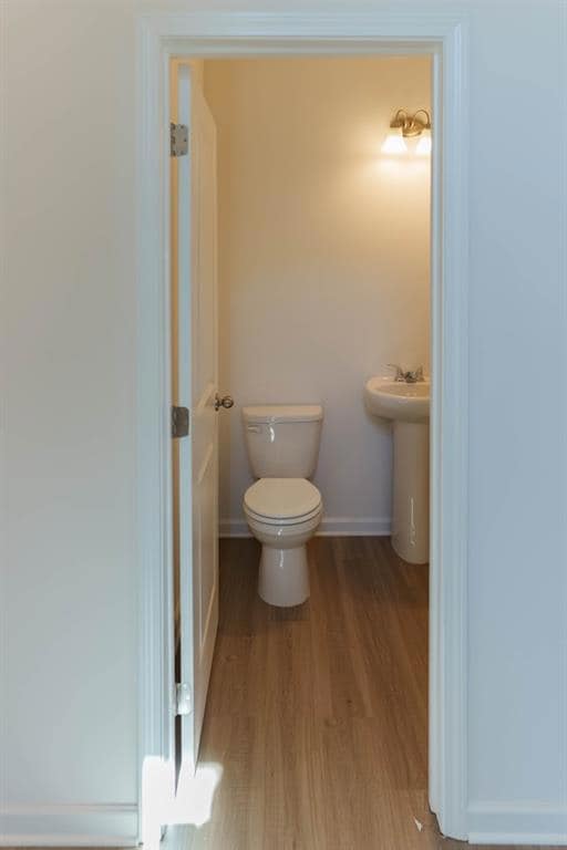 Half bath with baseboards, toilet, and wood finish