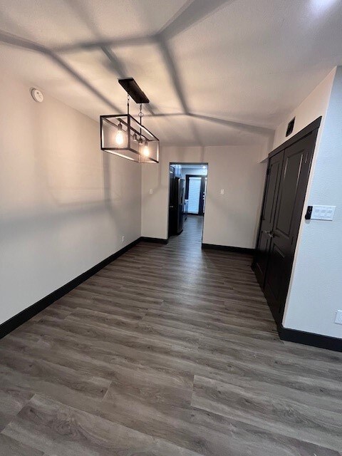Unfurnished dining area featuring baseboards and dark wood finished floors