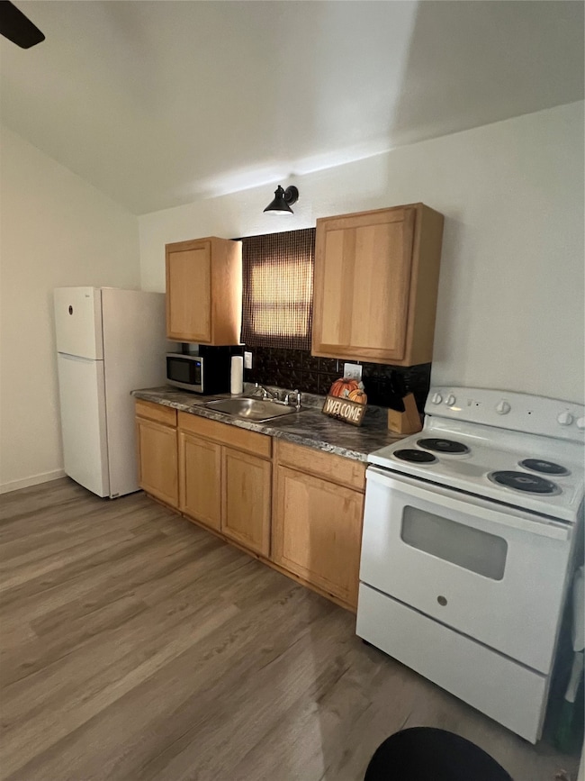 Kitchen featuring range, dark countertops, decorative backsplash, fridge, and light wood-style floors