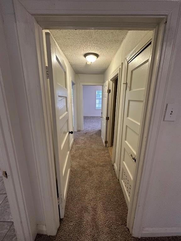 Hallway featuring a textured ceiling and carpet