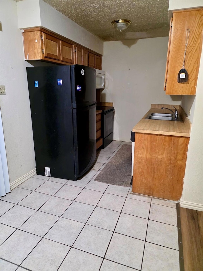 Kitchen with light tile patterned floors, a sink, 