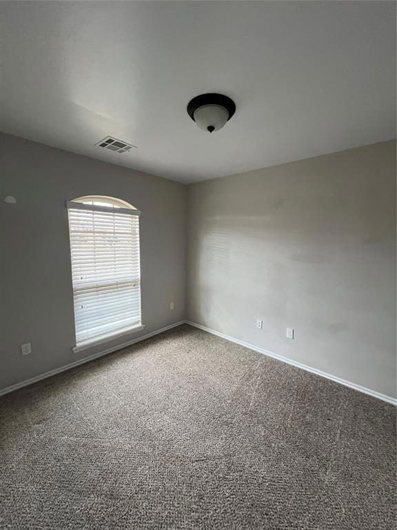 Carpeted spare room featuring baseboards