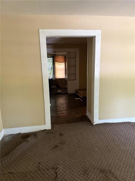 Hallway featuring carpet flooring and baseboards