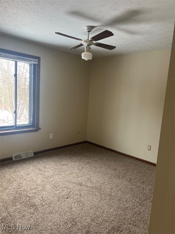 Carpeted spare room featuring ceiling fan and a textured ceiling