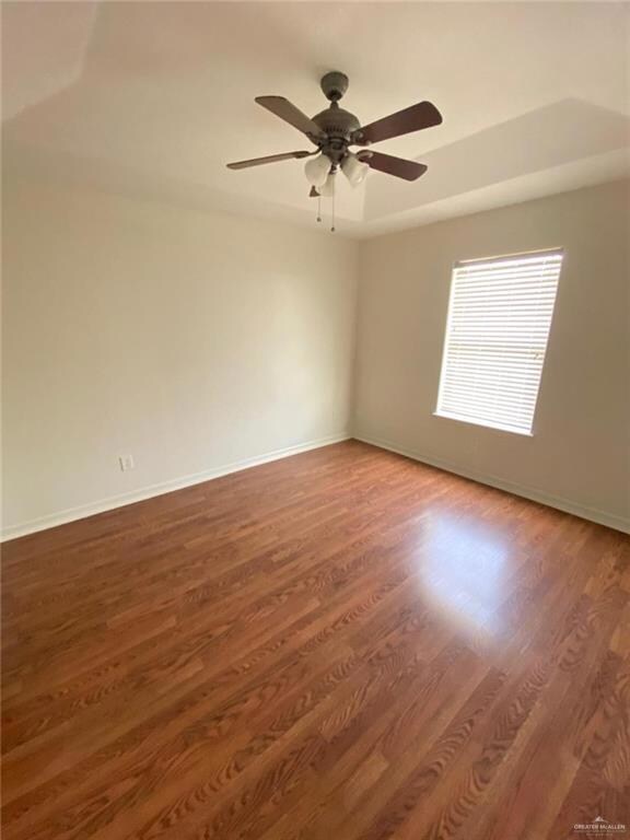 Empty room with ceiling fan, baseboards, and wood finished floors