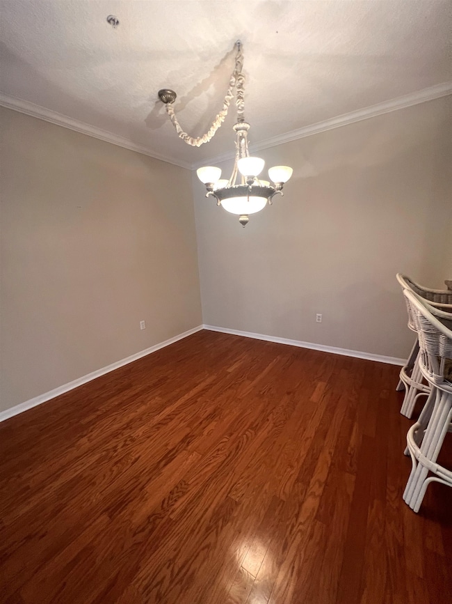 Unfurnished room with dark wood-style floors, crown molding, a chandelier, and a textured ceiling