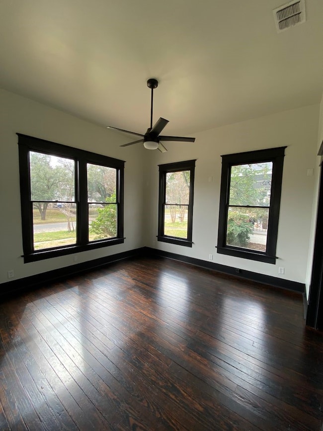 Unfurnished room with dark wood-style flooring and a ceiling fan