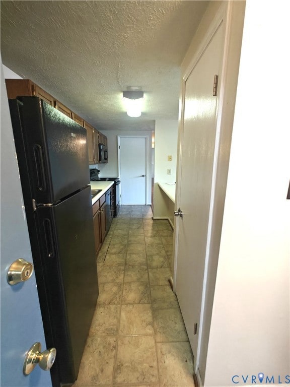 Kitchen featuring black appliances, light countertops, and a textured ceiling