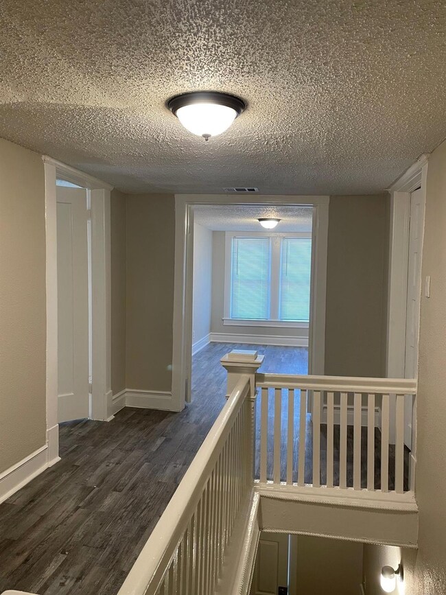 Hall featuring visible vents, a textured ceiling, 