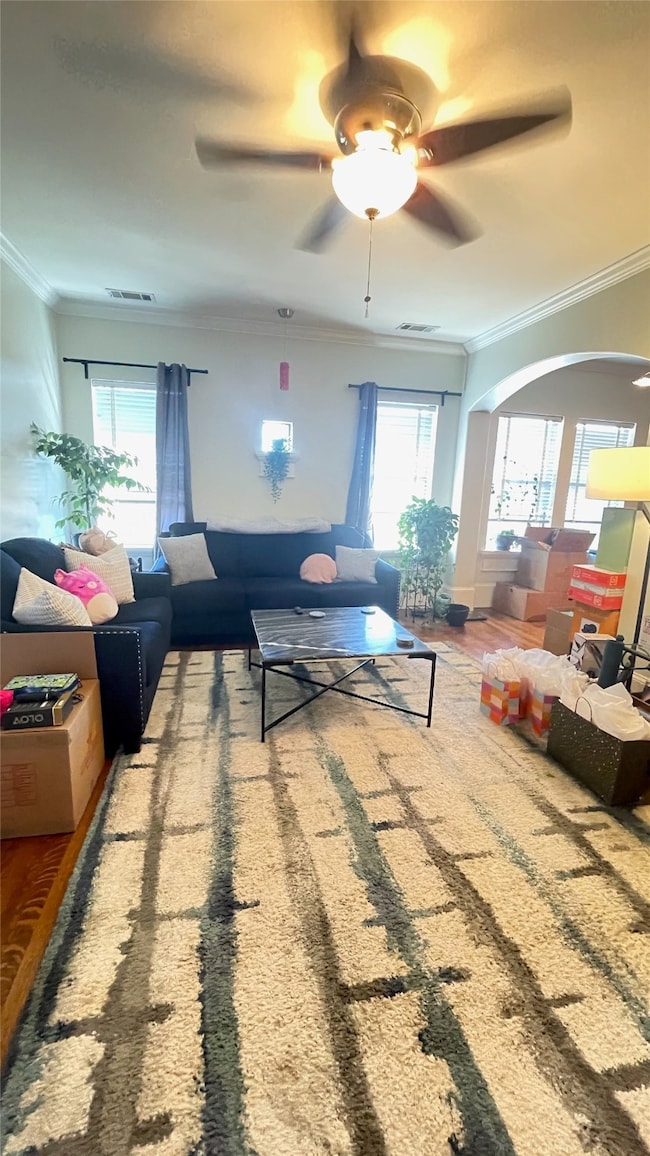 Full view of the living room featuring the arched transom into the kitchen, small alcove window, ceiling fan and original hardwood floors.