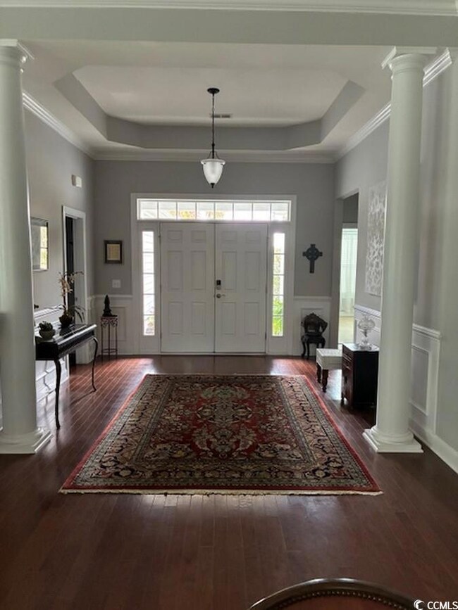 Entryway with decorative columns, a raised ceiling