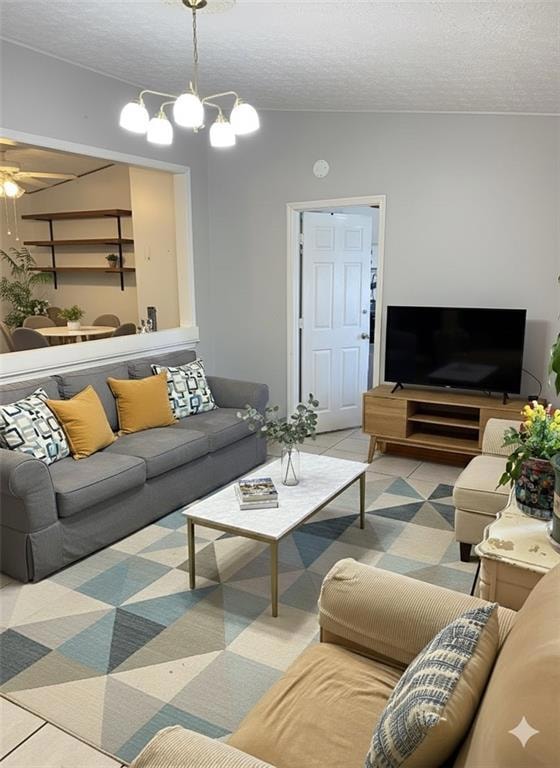 Tiled living room with a textured ceiling, a ceiling fan, and a chandelier. Staged Photo.
