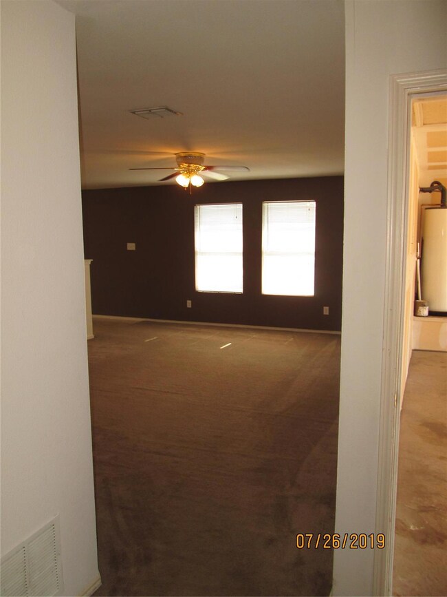 Unfurnished room with water heater, carpet flooring, and ceiling fan