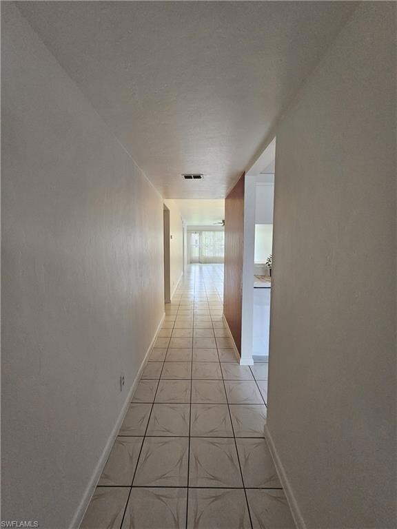 Corridor with light tile patterned floors and baseboards