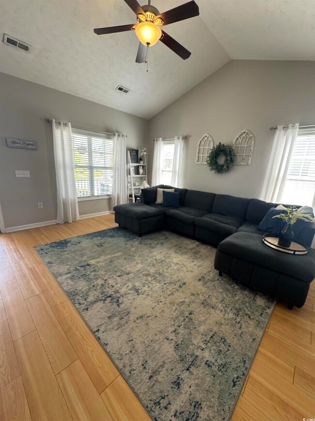 Living area featuring visible vents, ceiling fan, 