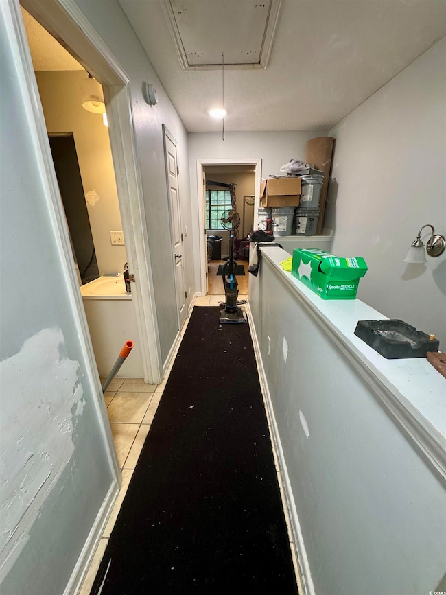 Hall featuring attic access and light tile patterned floors