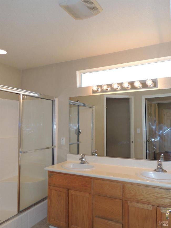 primary bathroom with double sinks and seated shower