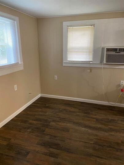 Empty room featuring dark wood-style flooring, ba