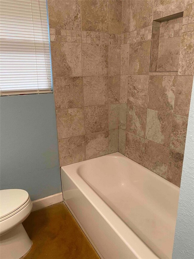 Full bath featuring toilet, baseboards, and tub /