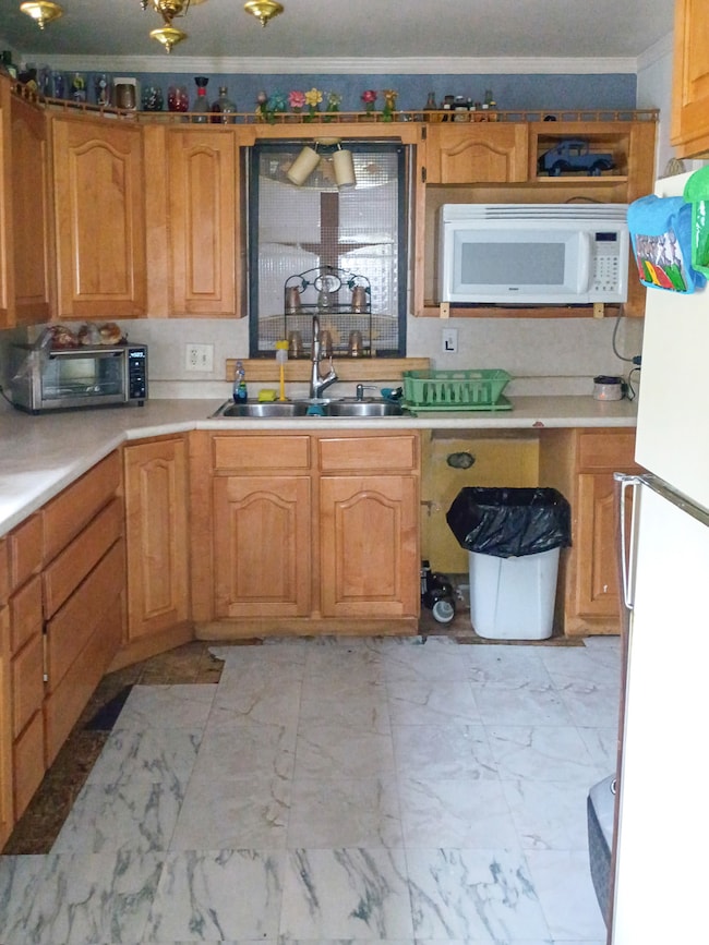 Kitchen featuring white appliances, light countertops, crown molding, and brown cabinets