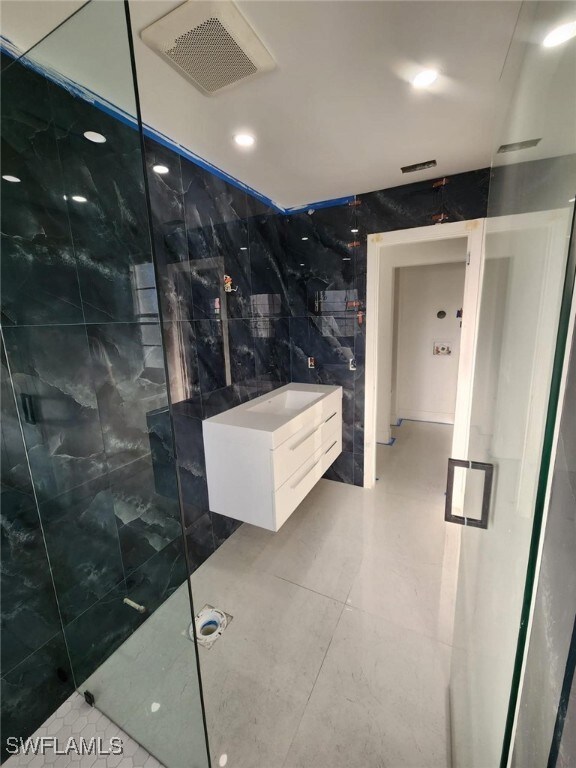 Bathroom featuring tile walls, an enclosed shower,