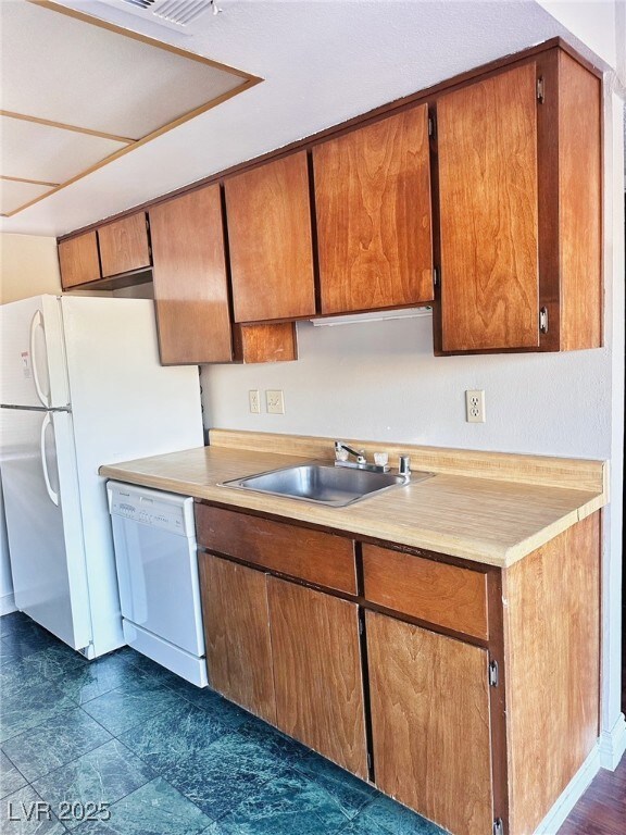 Kitchen with white appliances, a sink, light count