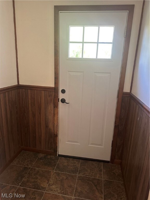 Entryway with wood walls and dark tile flooring