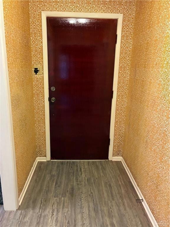 Hall featuring dark wood finished floors and wallpapered walls