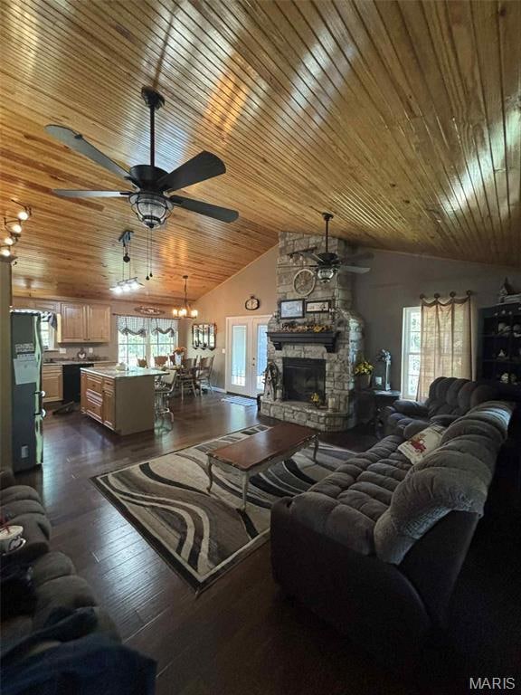 Living room with dark wood finished floors, wooden ceiling, a stone fireplace, ceiling fan, and high vaulted ceiling