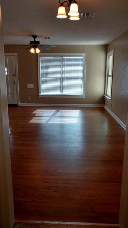 Unfurnished room featuring dark wood finished floors, a chandelier, and ceiling fan