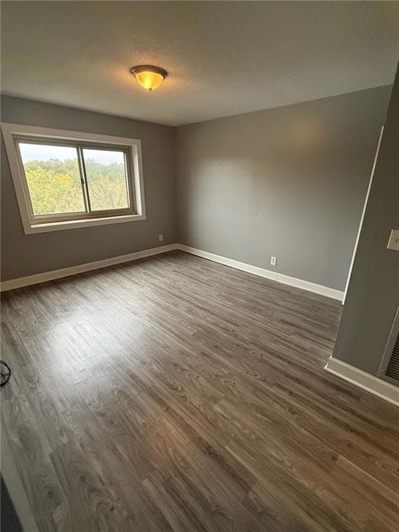 Spare room with dark wood-type flooring and a textured ceiling