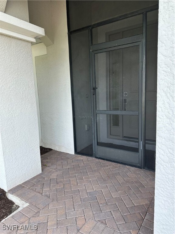 Property entrance with stucco siding and a patio